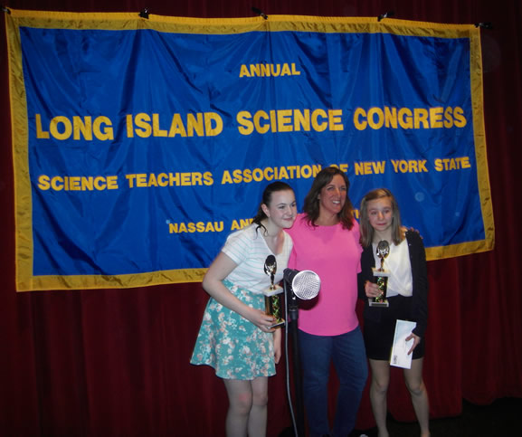 two students with science awards in front of banner