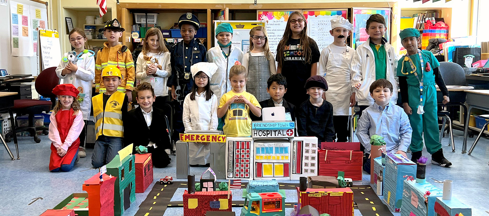 Students Standing Behind a Commumity Built From Cardboard Boxes
