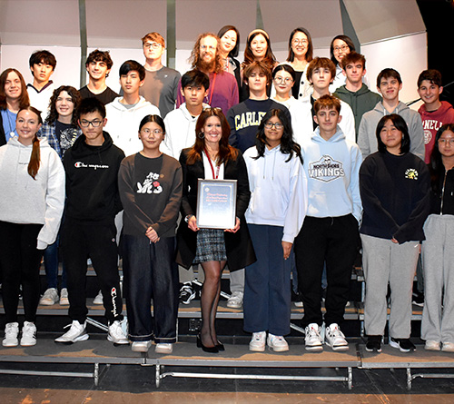 Class group photo featuring students and a teacher with an award.