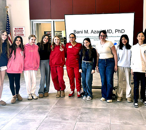 Group of students standing with a speaker during a medical career presentation indoors