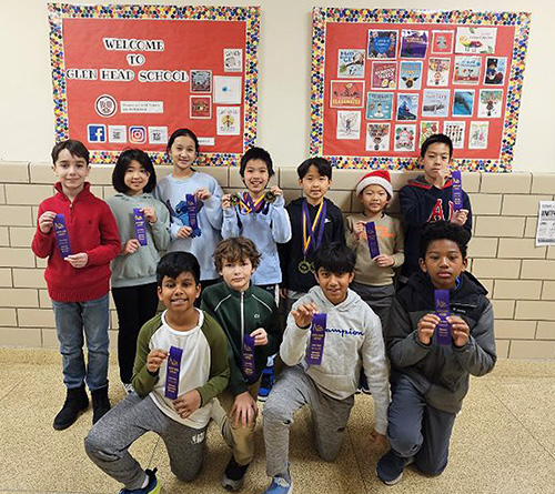 Group of students posing in a school hallway, holding purple award ribbons in front of bulletin boards.