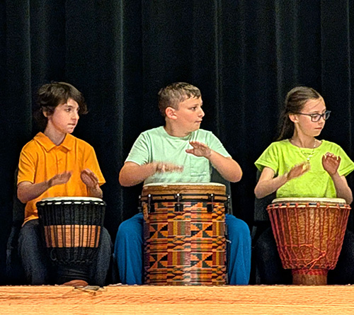 Group of children on stage holding certificates during a school recognition event.